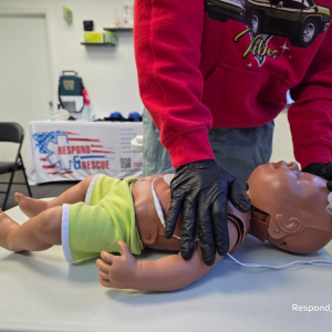 Instructor performing one-handed infant CPR during adult, child, and infant CPR AED training class.