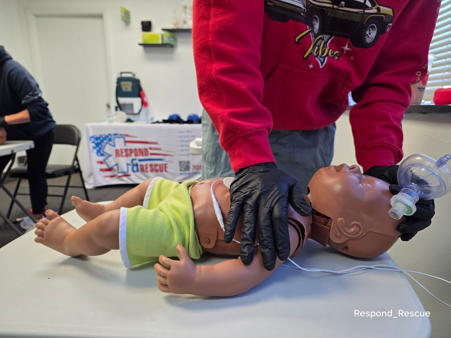 Instructor performing one-handed infant CPR during adult, child, and infant CPR AED training class.