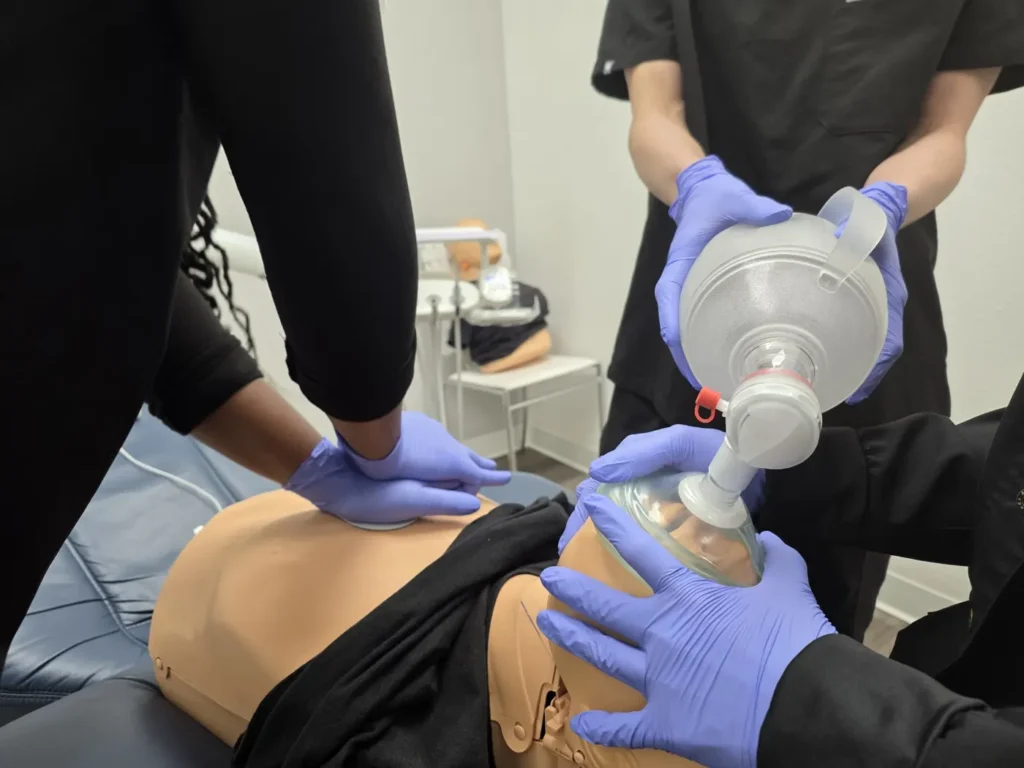 Dental office staff practicing BLS CPR with a bag-valve mask during on-site training by Respond and Rescue