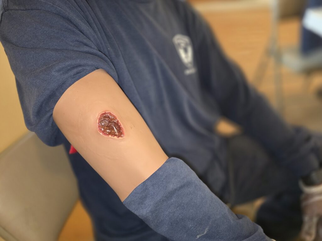 Embedded object wound simulator on a student's arm during a first aid training class for construction crews
