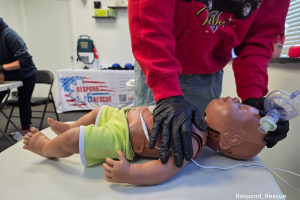 Instructor performing one-handed infant CPR during adult, child, and infant CPR AED training class.