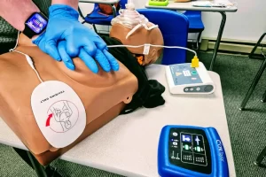 Student performing adult CPR chest compressions on a manikin during American Red Cross CPR AED training.